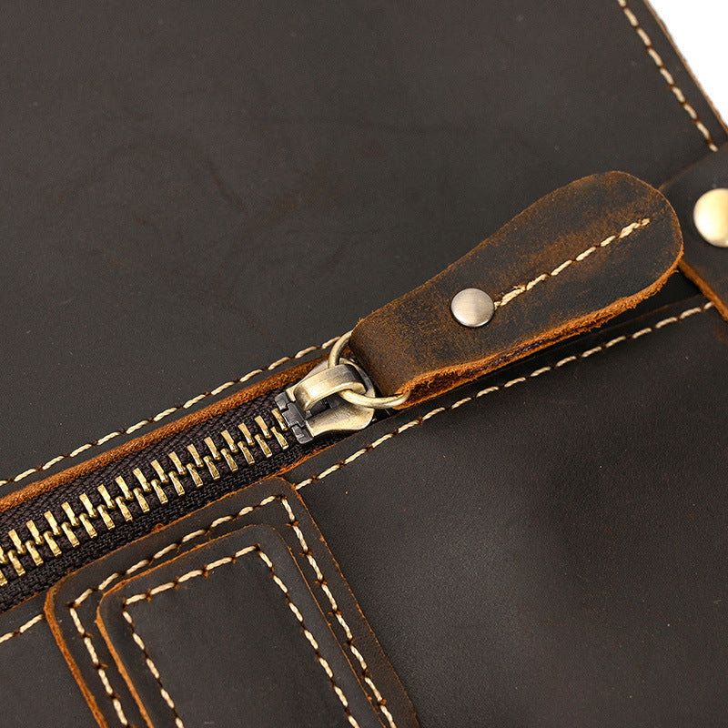 Close-up of the gold-tone zip pull and stitching on the dark brown briefcase
